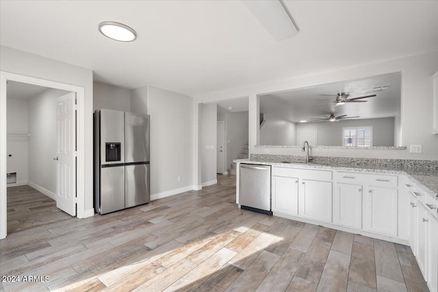 kitchen with appliances with stainless steel finishes, light stone counters, sink, light hardwood / wood-style flooring, and white cabinets