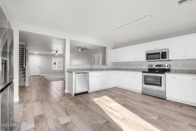 kitchen featuring white cabinets, light hardwood / wood-style flooring, ceiling fan, light stone counters, and stainless steel appliances