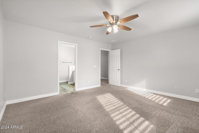 unfurnished bedroom featuring ceiling fan, light colored carpet, and ensuite bath