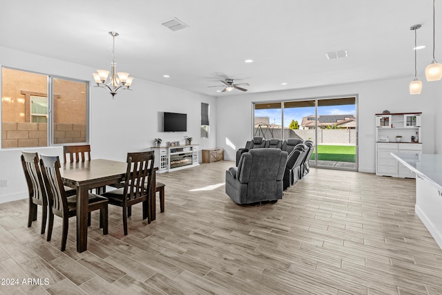 dining area featuring a healthy amount of sunlight, ceiling fan with notable chandelier, and light wood-type flooring