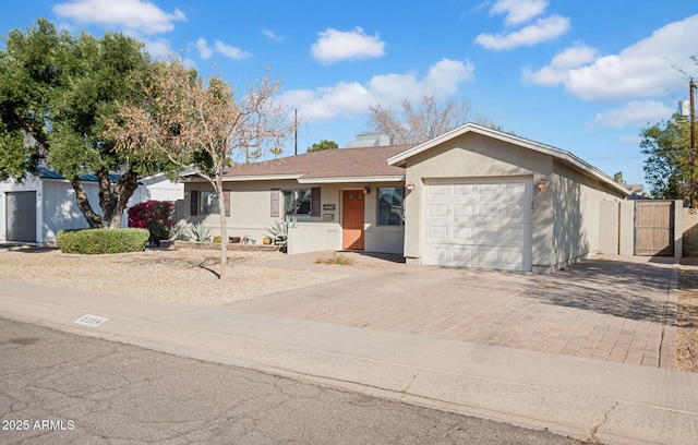 ranch-style home featuring a gate, roof with shingles, stucco siding, a garage, and decorative driveway