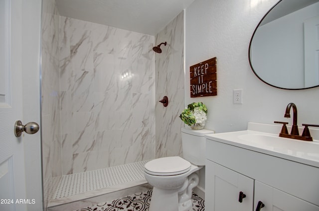 bathroom with vanity, a tile shower, and toilet