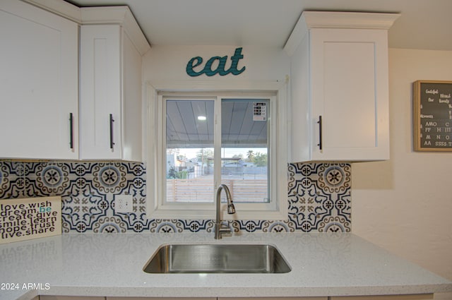 kitchen featuring sink, white cabinets, and light stone counters