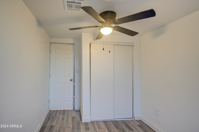 unfurnished bedroom featuring hardwood / wood-style flooring, ceiling fan, and a closet