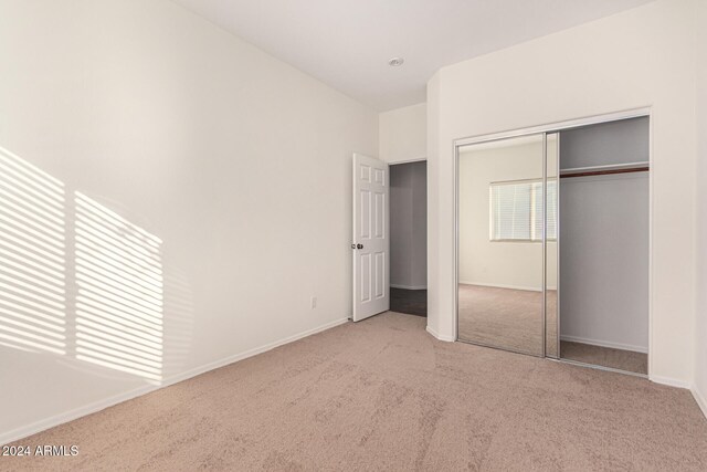 unfurnished bedroom with light carpet and a closet