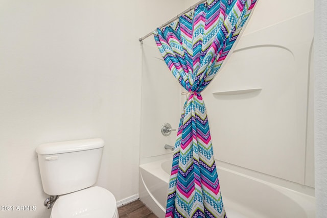 bathroom featuring shower / bath combination with curtain, hardwood / wood-style flooring, and toilet