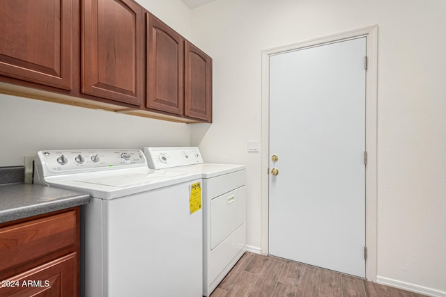 laundry area with cabinets, light wood-type flooring, and washing machine and clothes dryer