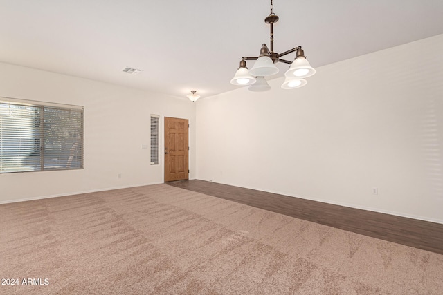 spare room with wood-type flooring and a notable chandelier