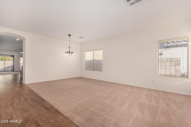 unfurnished room featuring wood-type flooring and ceiling fan with notable chandelier