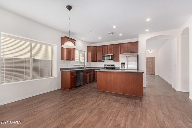 kitchen featuring hanging light fixtures, a center island, dark wood-type flooring, and appliances with stainless steel finishes