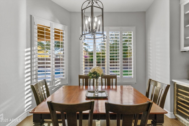 dining area with light wood-type flooring, beverage cooler, and an inviting chandelier