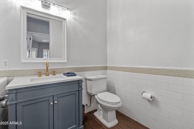 bathroom with toilet, vanity, and tile walls