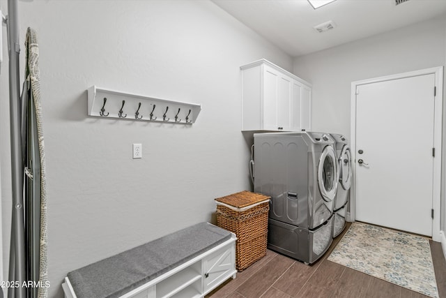 clothes washing area with washing machine and dryer and cabinets