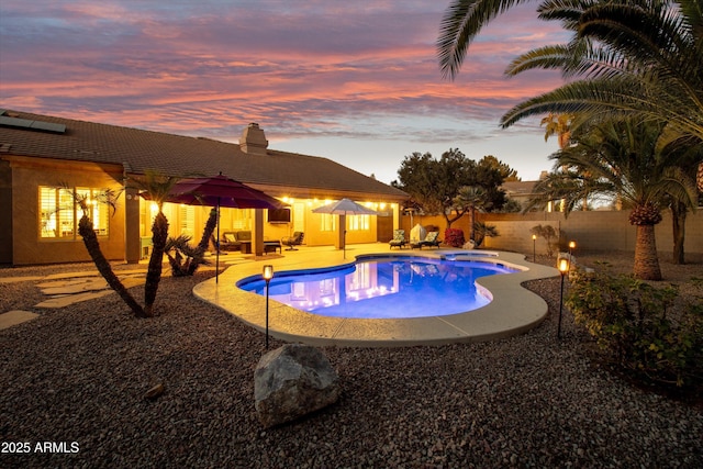 pool at dusk with a patio area and an in ground hot tub