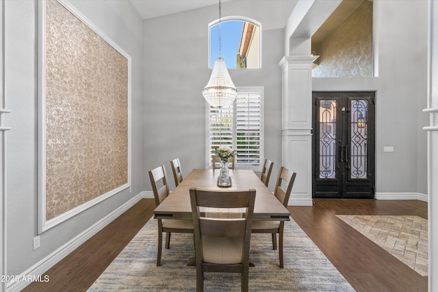 dining room with a high ceiling, french doors, dark hardwood / wood-style floors, and a notable chandelier