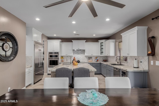16178 W Granada Rd, Goodyear, AZ 85395 - kitchen featuring stainless steel appliances, ceiling fan, an island with sink, tasteful backsplash, and white cabinetry