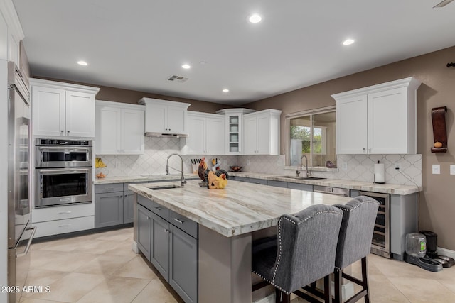16178 W Granada Rd, Goodyear, AZ 85395 - kitchen with gray cabinets, stainless steel appliances, white cabinets, a kitchen island with sink, and tasteful backsplash
