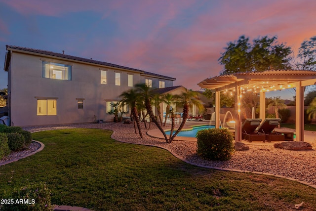 16178 W Granada Rd, Goodyear, AZ 85395 - back of house at dusk with a pergola, a lawn, a patio area, an outdoor pool, and stucco siding