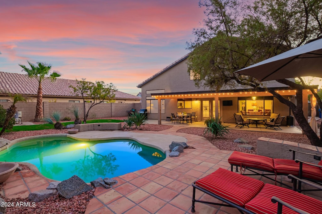 pool at dusk featuring a patio area