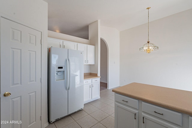 kitchen with white cabinetry, light tile patterned floors, decorative light fixtures, white refrigerator with ice dispenser, and a notable chandelier