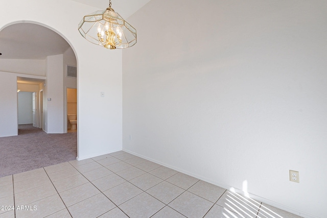 empty room featuring light tile patterned floors, vaulted ceiling, and an inviting chandelier