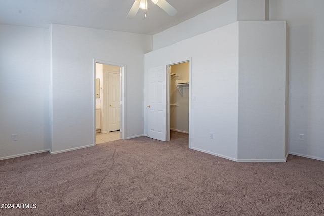 unfurnished bedroom with a spacious closet, light carpet, ceiling fan, and a closet