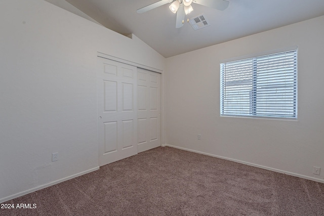 unfurnished bedroom with a closet, lofted ceiling, ceiling fan, and carpet floors