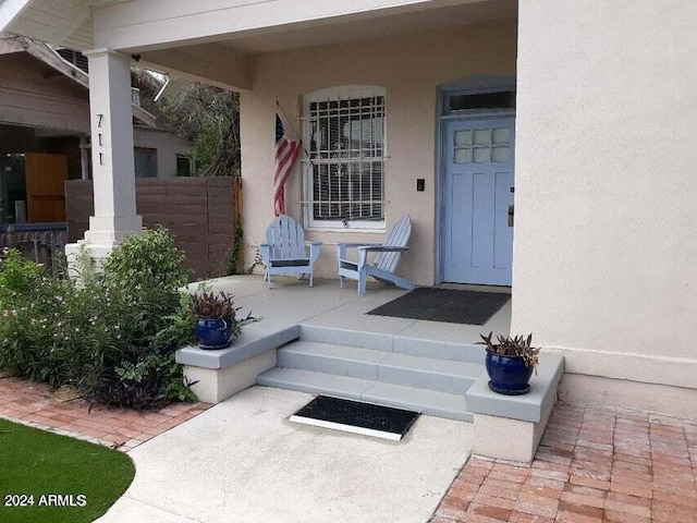 entrance to property featuring stucco siding and fence