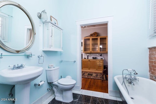 bathroom featuring baseboards, toilet, and a soaking tub