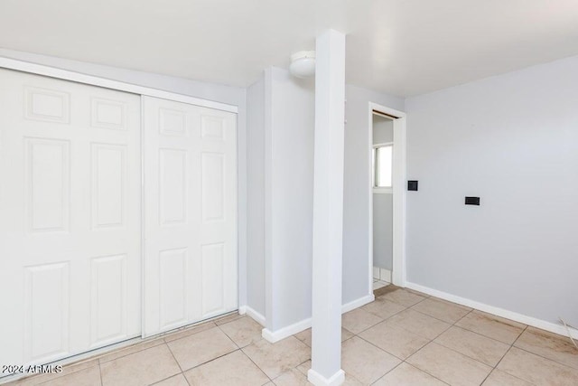 unfurnished bedroom with a closet, light tile patterned flooring, and baseboards