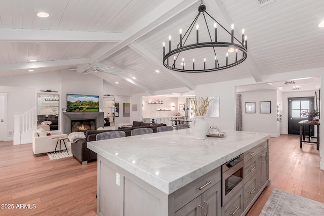 6196 E Calle Camelia, Scottsdale, AZ 85251 - kitchen with stainless steel microwave, gray cabinets, light wood finished floors, a kitchen island, and open floor plan