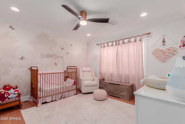 6196 E Calle Camelia, Scottsdale, AZ 85251 - bedroom with wood finished floors, a crib, ornamental molding, a ceiling fan, and recessed lighting