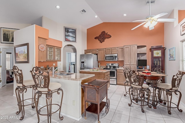 kitchen featuring a breakfast bar, sink, a center island, stainless steel appliances, and light stone countertops