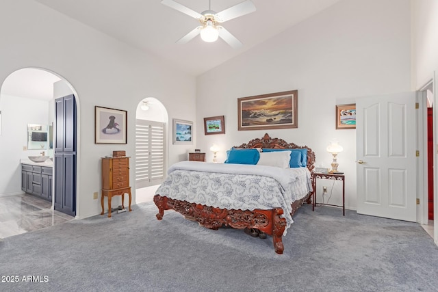 carpeted bedroom featuring ceiling fan, high vaulted ceiling, and ensuite bath