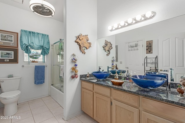 full bathroom featuring tile patterned flooring, bath / shower combo with glass door, vanity, and toilet