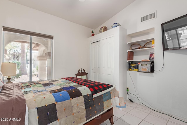 bedroom with vaulted ceiling, a closet, and light tile patterned floors