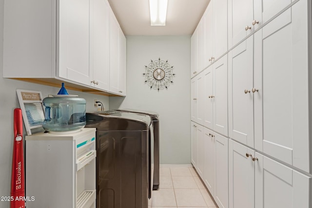 washroom featuring light tile patterned floors, washer and clothes dryer, and cabinets