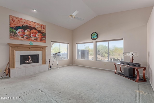 unfurnished living room with a tiled fireplace, ceiling fan, light colored carpet, and high vaulted ceiling