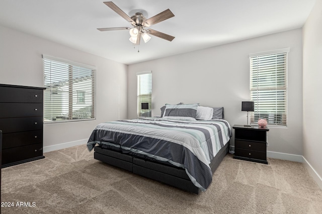 bedroom with multiple windows, ceiling fan, and light carpet