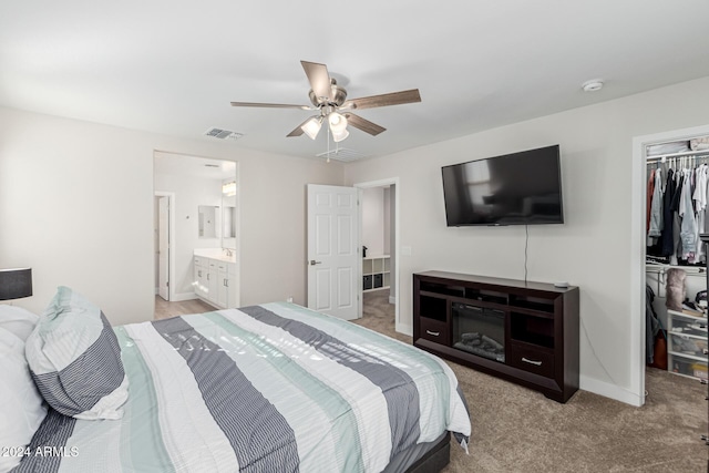 bedroom with light carpet, a walk in closet, ensuite bathroom, ceiling fan, and a closet