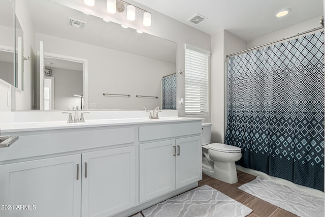 bathroom featuring hardwood / wood-style floors, vanity, toilet, and curtained shower