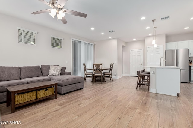 living room with light hardwood / wood-style floors and ceiling fan