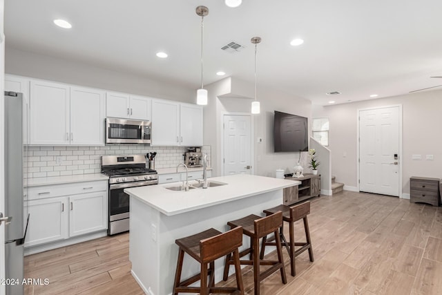 kitchen featuring sink, white cabinets, decorative light fixtures, and appliances with stainless steel finishes