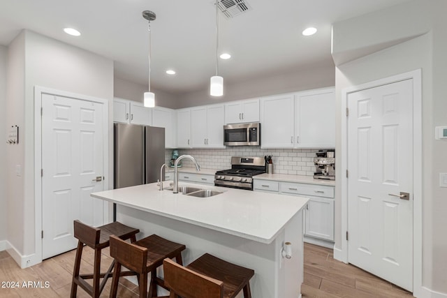 kitchen with a center island with sink, sink, white cabinetry, and stainless steel appliances