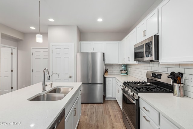 kitchen featuring backsplash, stainless steel appliances, sink, pendant lighting, and white cabinetry