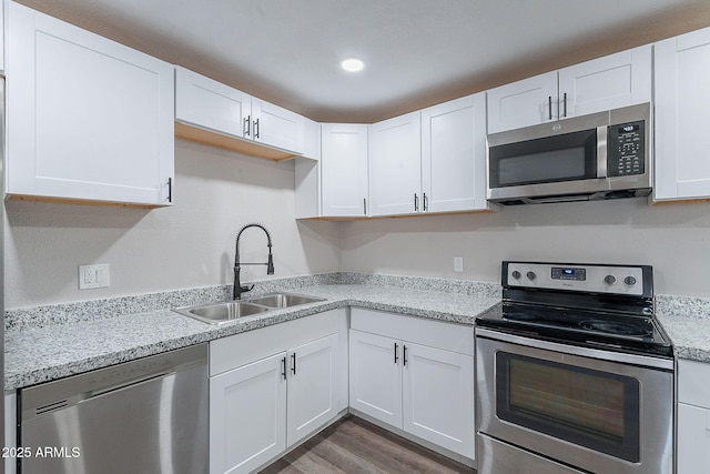 kitchen featuring a sink, white cabinetry, appliances with stainless steel finishes, and wood finished floors
