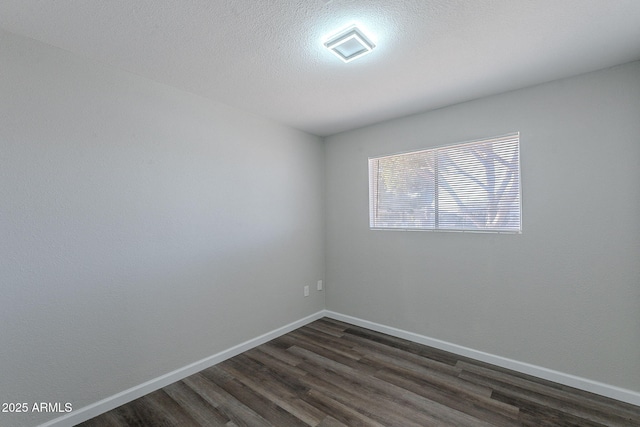 spare room featuring baseboards and dark wood finished floors