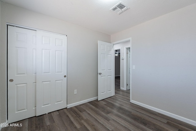 unfurnished bedroom with baseboards, visible vents, and dark wood finished floors