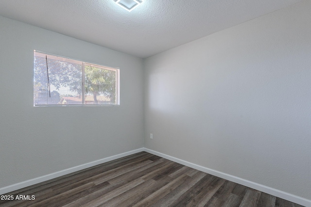 spare room with a textured ceiling, baseboards, visible vents, and dark wood-style floors