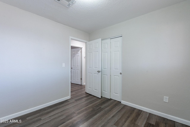 unfurnished bedroom with baseboards, visible vents, and dark wood-type flooring